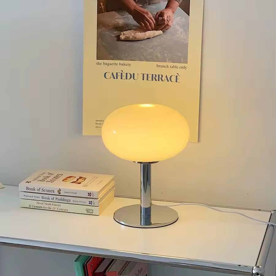 Yellow table lamp on a shelf with books and a poster in the background