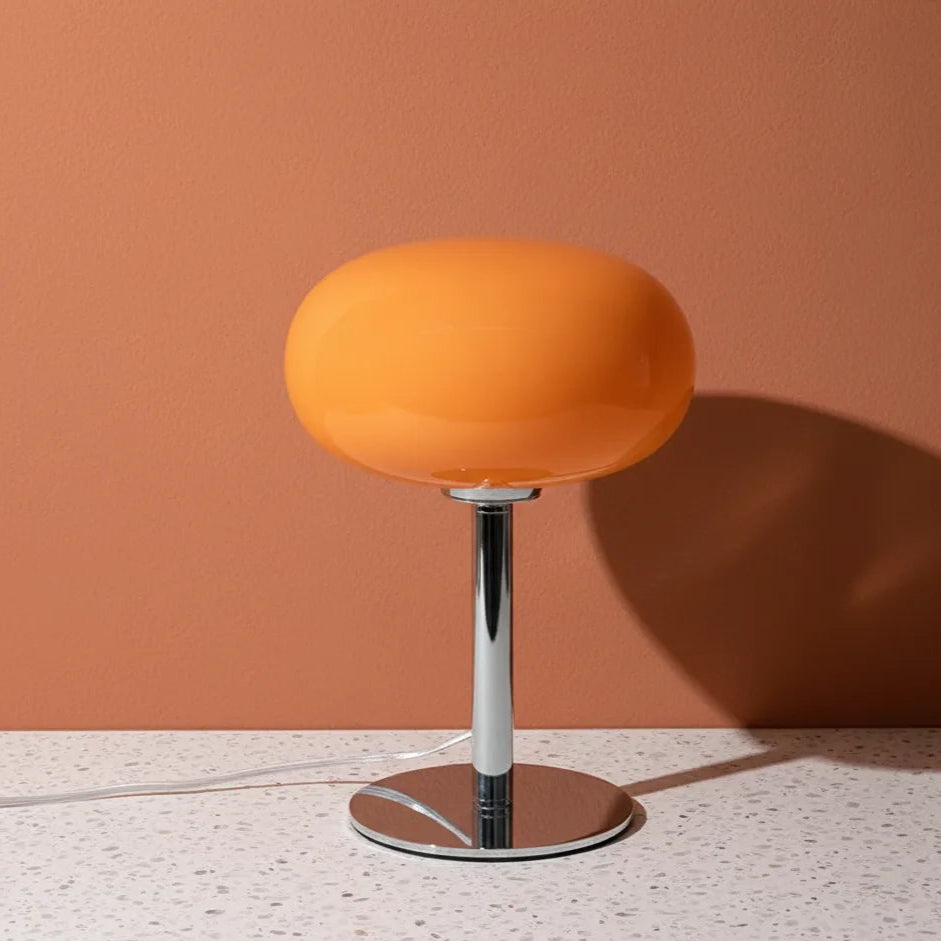 Orange lamp with a metallic base on a terracotta wall background