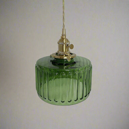 Green glass pendant light with brass fitting on a gray background