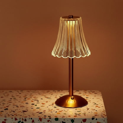 A glass table lamp on a terazzo surface ommiting a warm light.