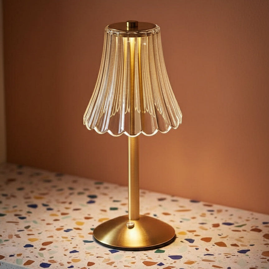 A glass table lamp on a terazzo surface ommiting a warm light.