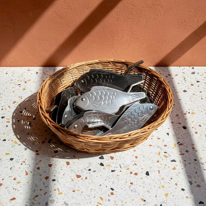 Wicker basket with metal fish-shaped objects on a terrazzo surface