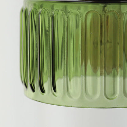 Close-up of a green glass jar with ribbed texture on a white background