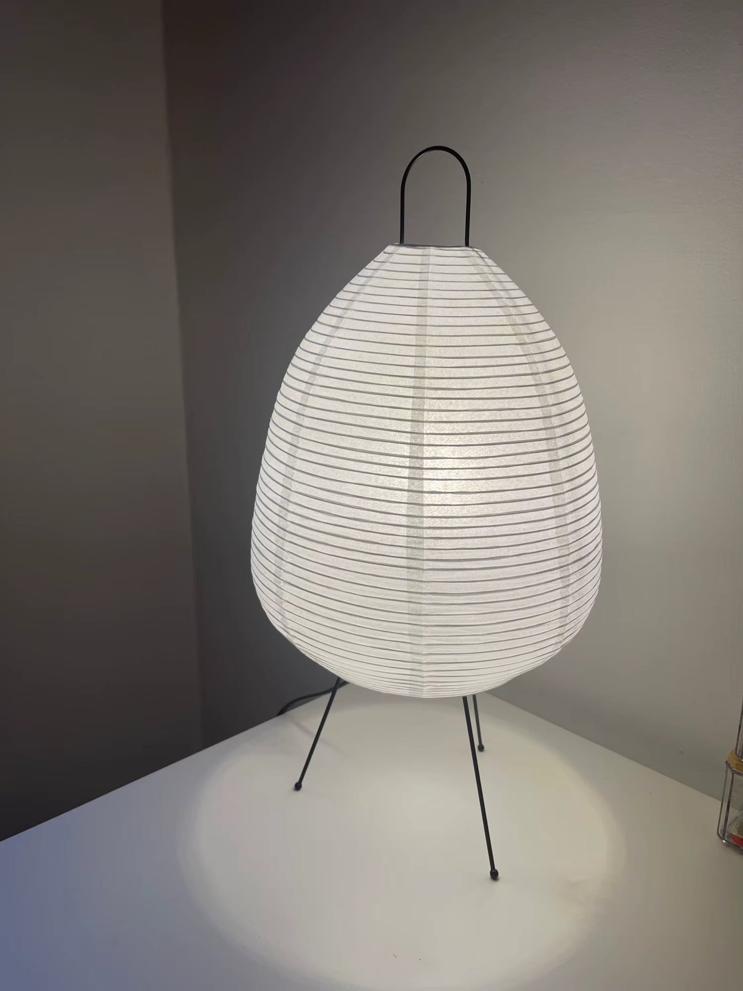 Modern lamp with white woven shade and black metal stand on a neutral background