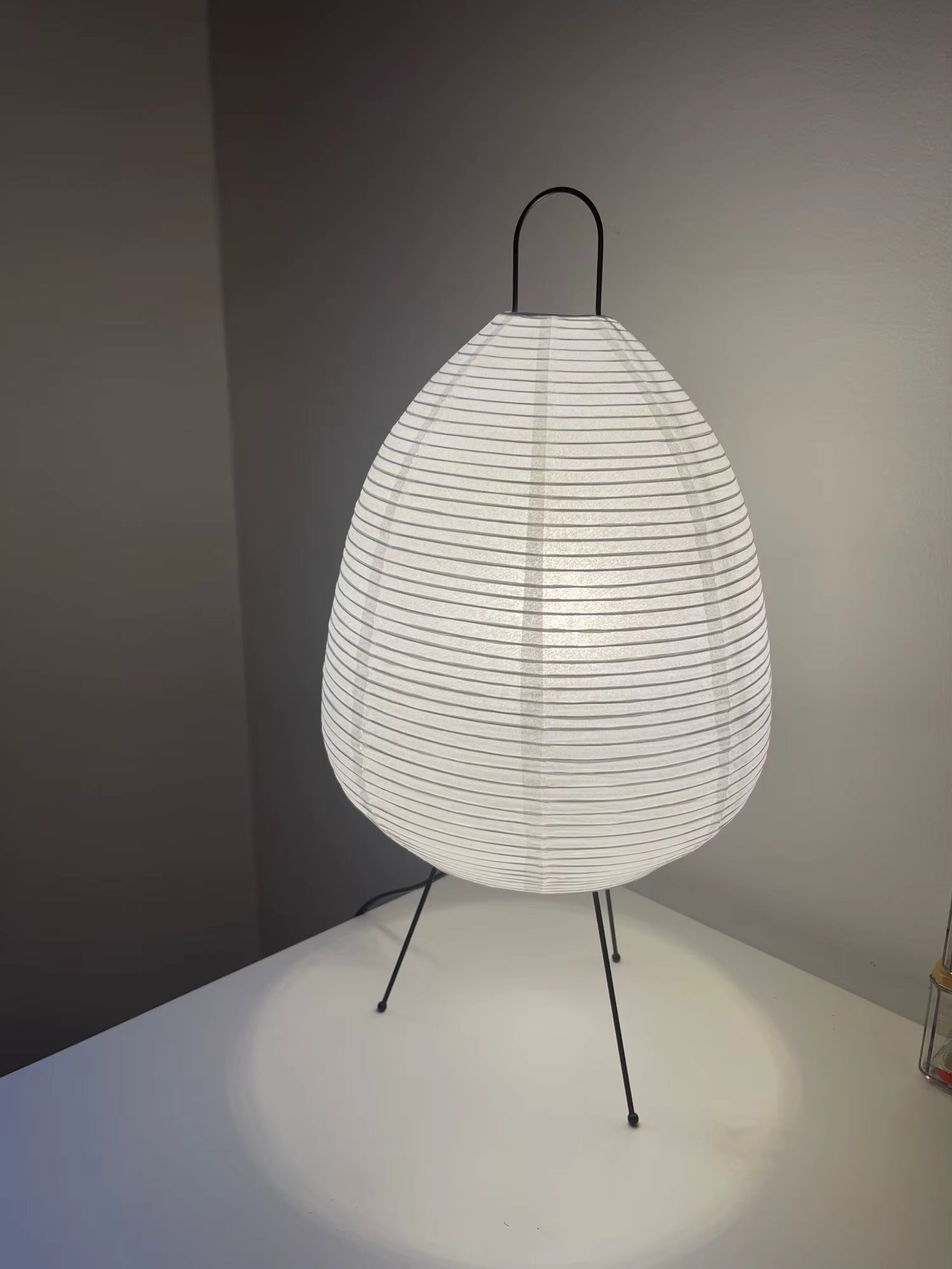 Modern lamp with white woven shade and black metal stand on a neutral background