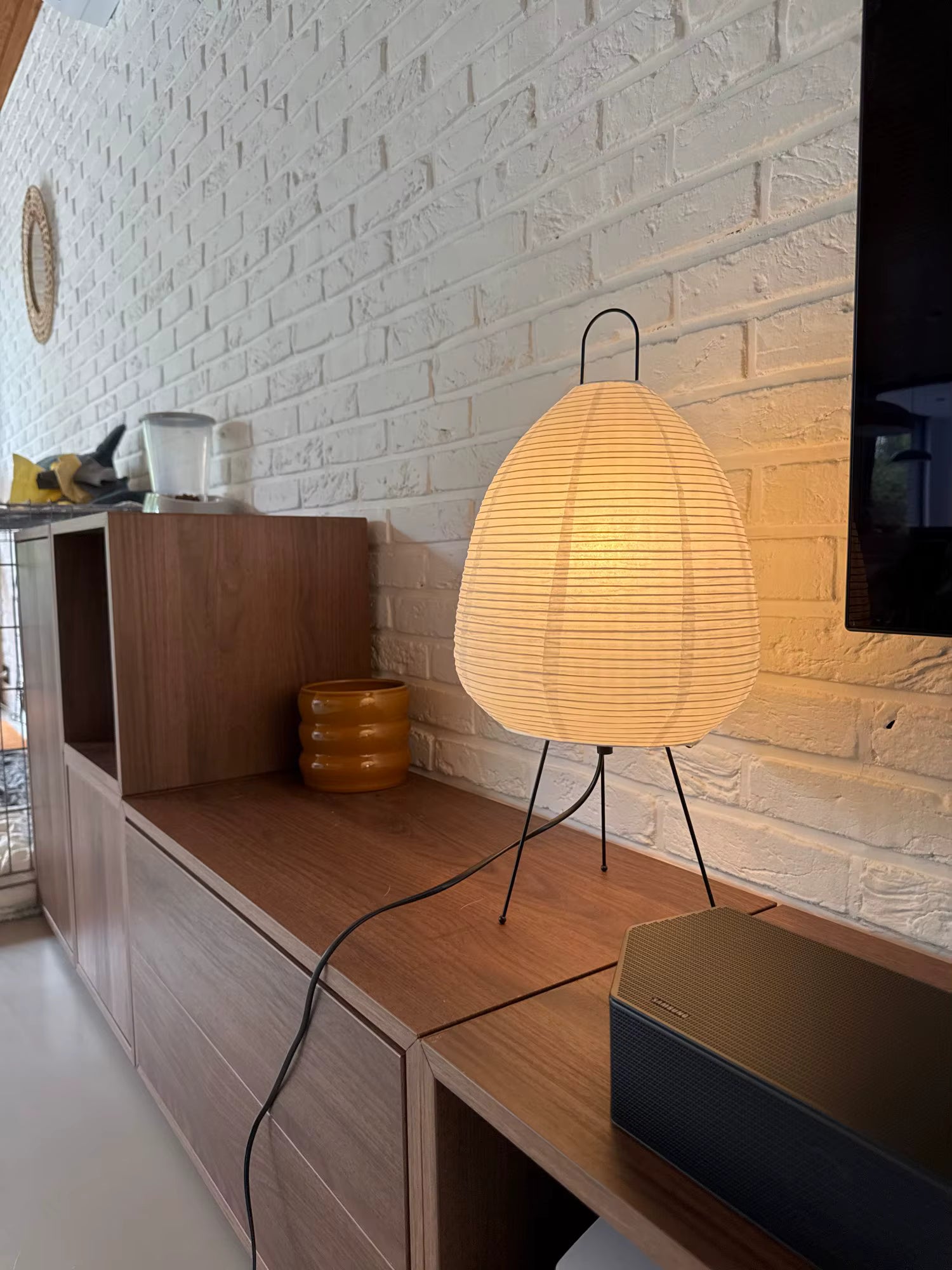 Lamp on a wooden shelf against a white brick wall