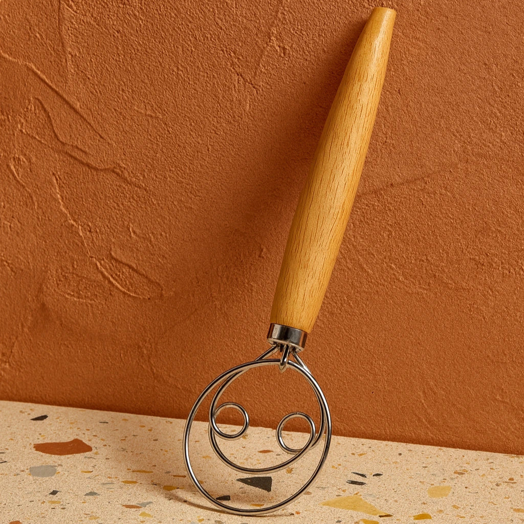 Metallic kitchen tool with wooden handle on terrazzo surface and orange wall