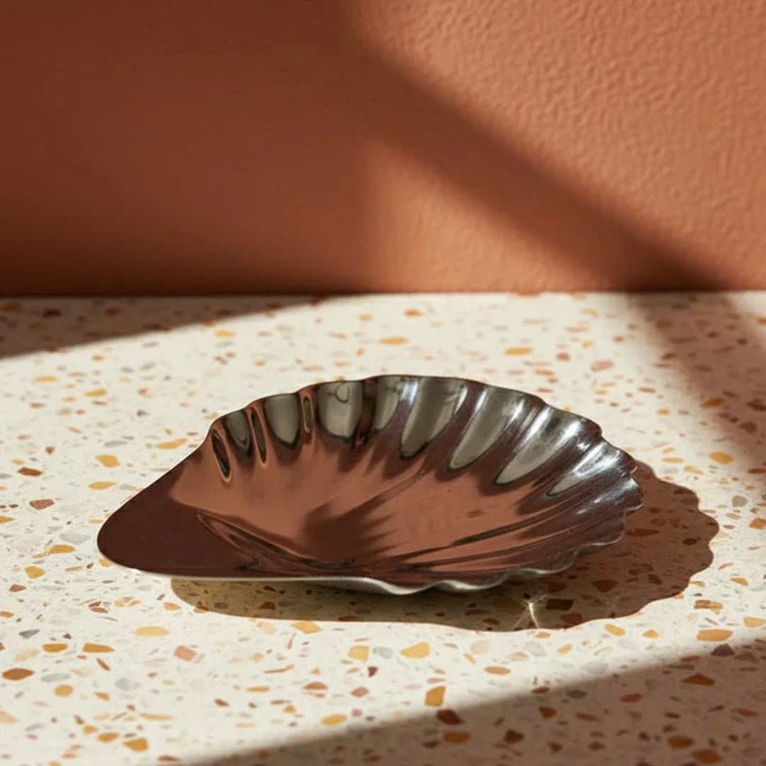 Decorative shell-shaped dish on a terrazzo surface with a warm background