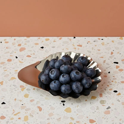 Silver leaf-shaped dish with blueberries on a terrazzo countertop