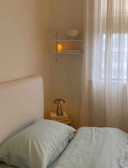 Bedroom with a bed, nightstand, and shelf with decorative items.