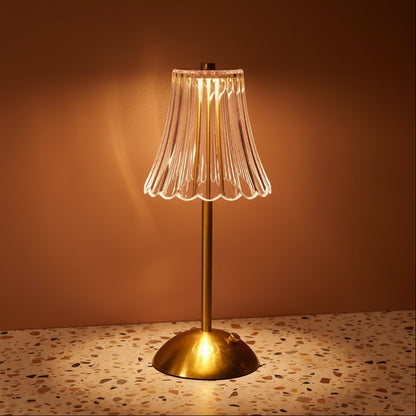 A glass table lamp on a terazzo surface ommiting a warm light.