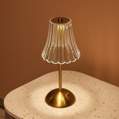 A glass table lamp on a terazzo surface ommiting a warm light.