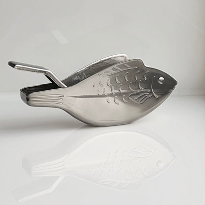 Metallic fish-shaped scoop on a light gray background