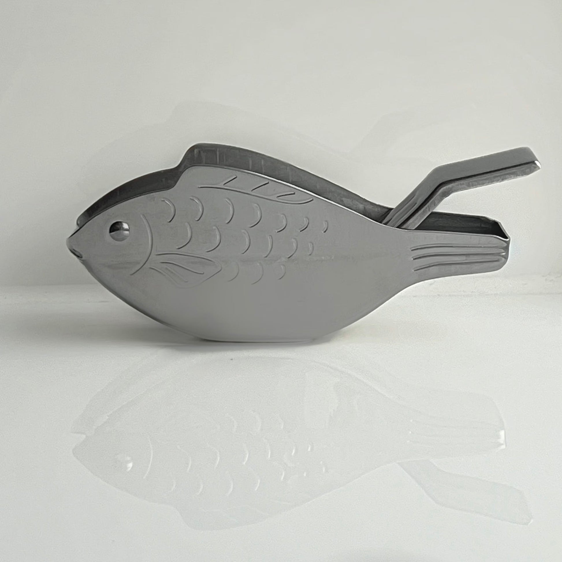 Gray fish-shaped tool on a light gray background