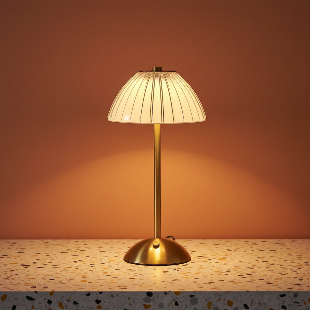 A glass fluted table lamp on a terazzo work surface omitting a soft, warm light.