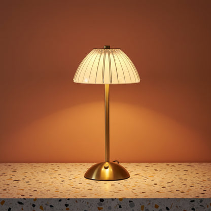 A glass fluted table lamp on a terazzo work surface omitting a soft, warm light.
