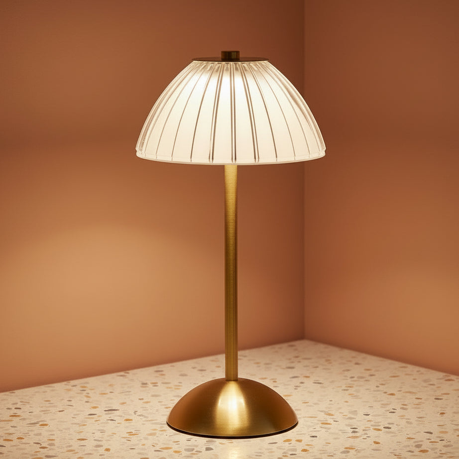 A glass fluted table lamp on a terazzo work surface omitting a cool light.