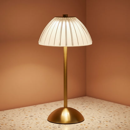 A glass fluted table lamp on a terazzo work surface omitting a cool light.