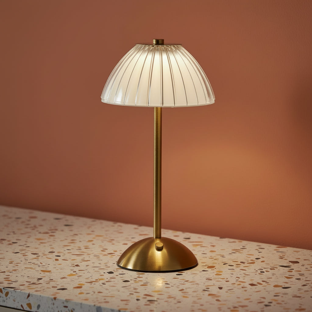 A glass fluted table lamp on a terazzo work surface omitting a cool light.
