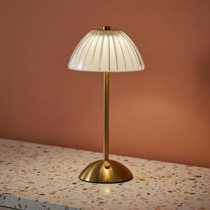 A glass fluted table lamp on a terazzo work surface omitting a cool light.