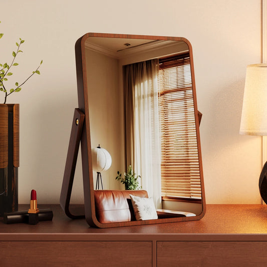 Wooden vanity mirror on a dresser with a lamp and plant in the background