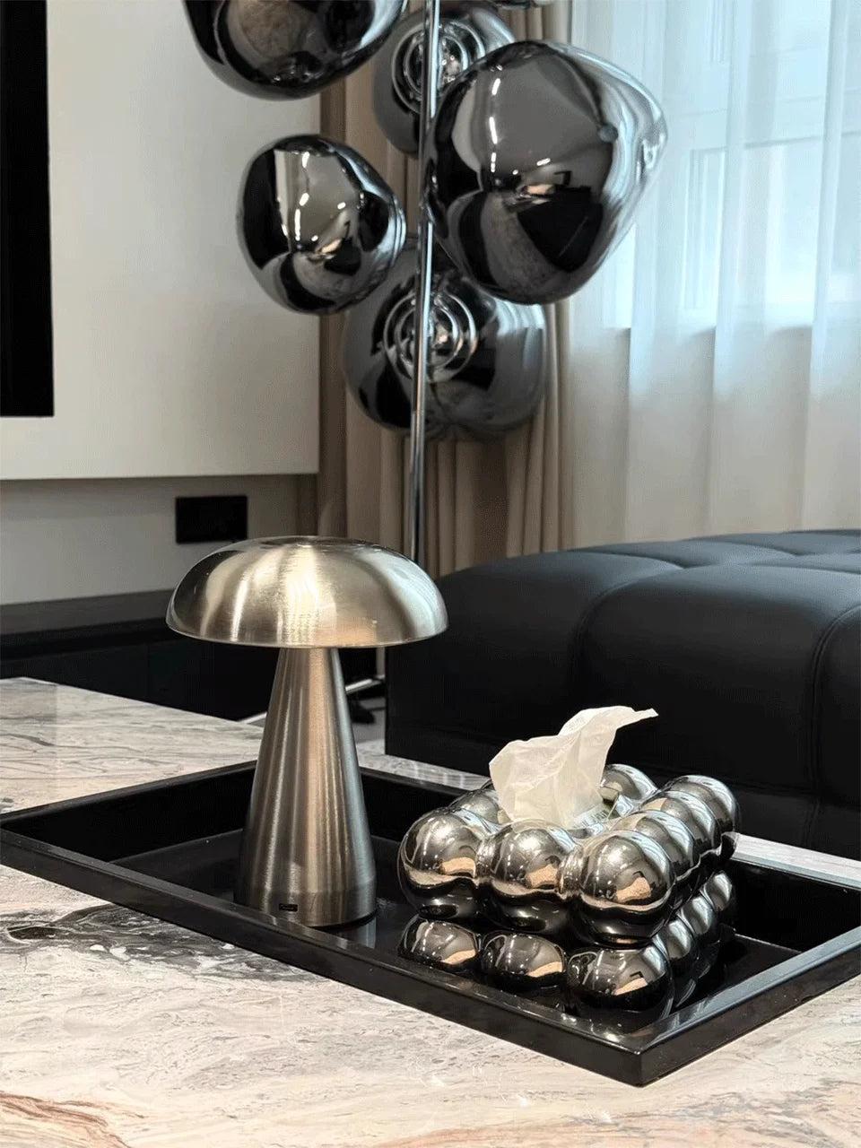 Modern interior decor with metallic lamp, decorative balls, and black sofa.