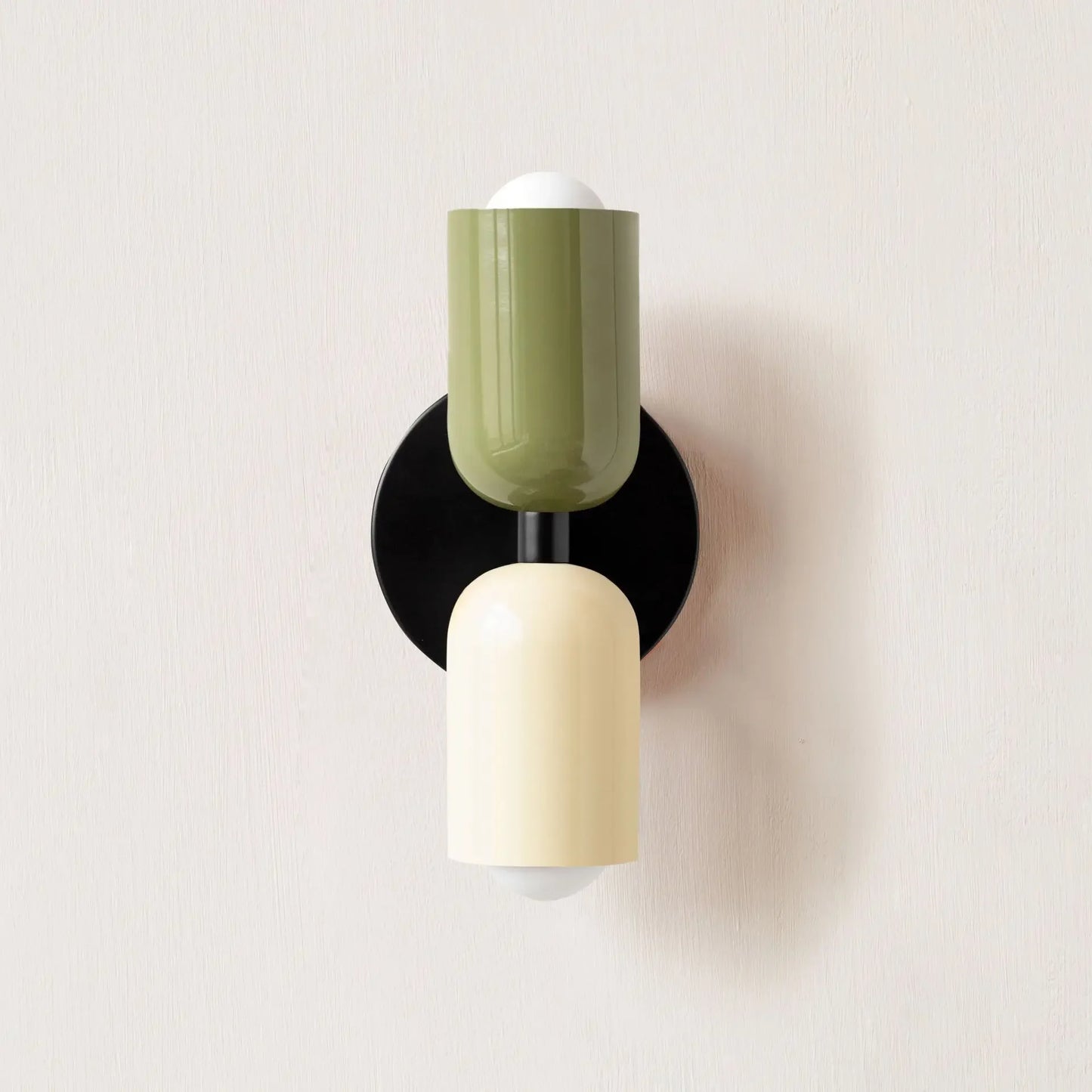 Modern wall light fixture with green and beige cylindrical design on a white background