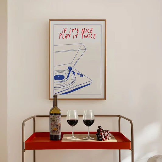 Framed artwork with a quote above a table with wine and grapes.
