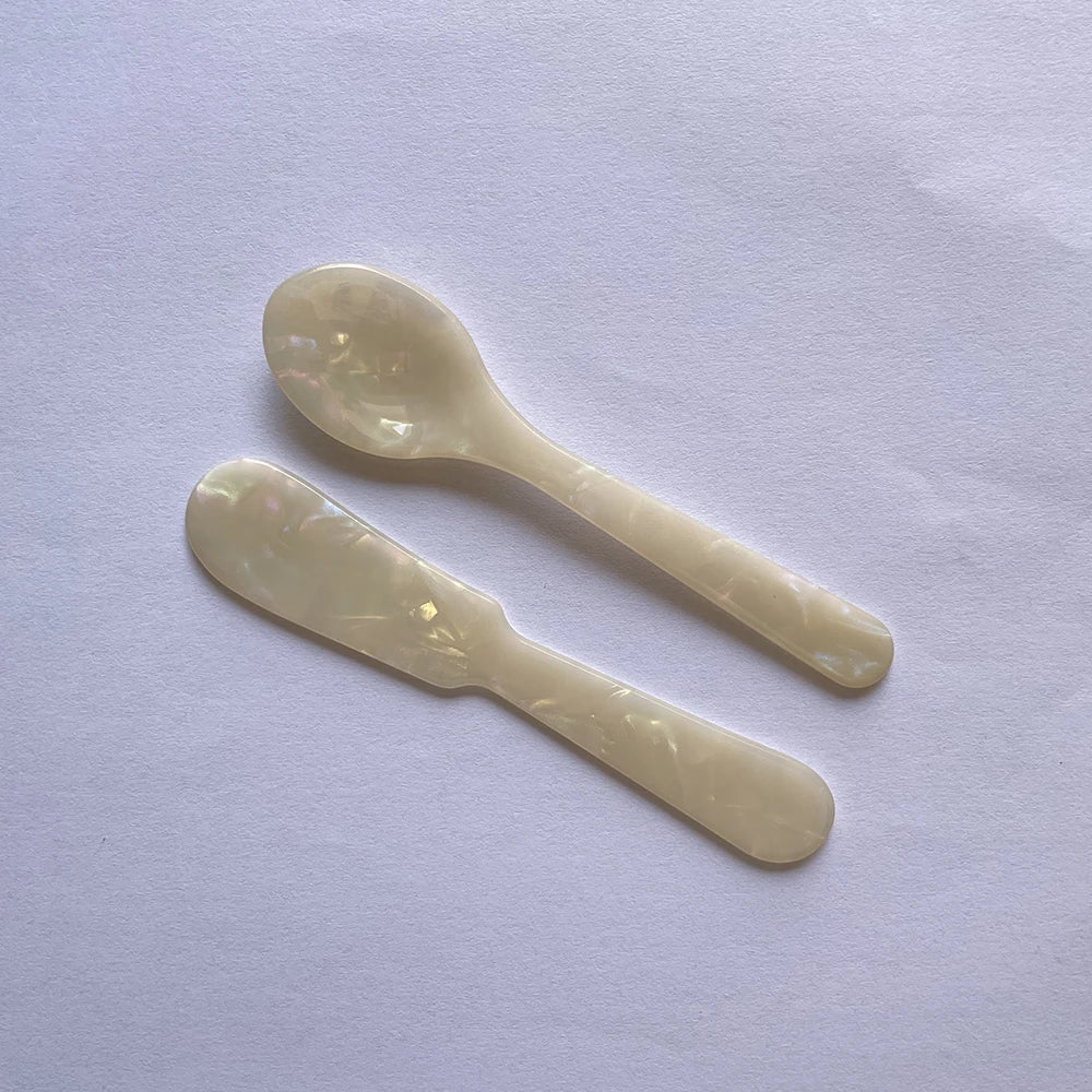 Two white plastic spoons on a light purple background