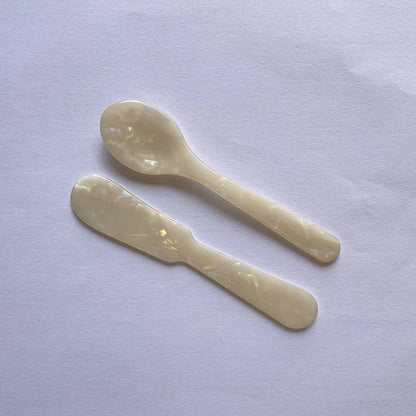Two white plastic spoons on a light purple background