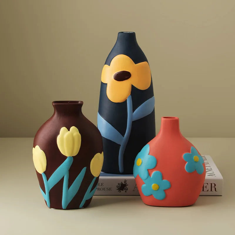 Three decorative vases with floral designs on a beige surface.