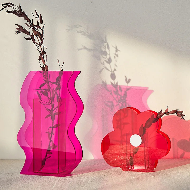 Pink wavy vase and a red flower vase on a white backdrop with sun reflecting