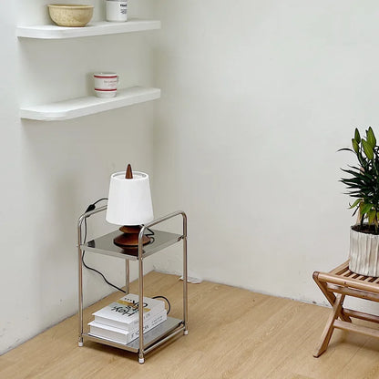 A metal storage cart with a lamp on it undernearth shelving