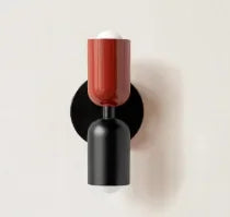 Wall-mounted light fixture with a red top and black base on a beige background