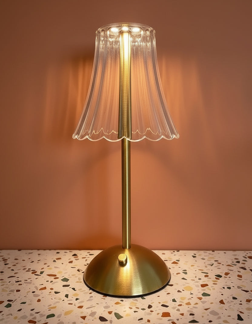 A glass table lamp on a terazzo surface ommiting a warm light.