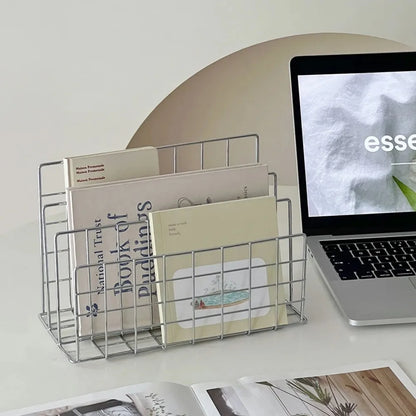 Metal magazine holder with books and a laptop displaying an image on a white surface.