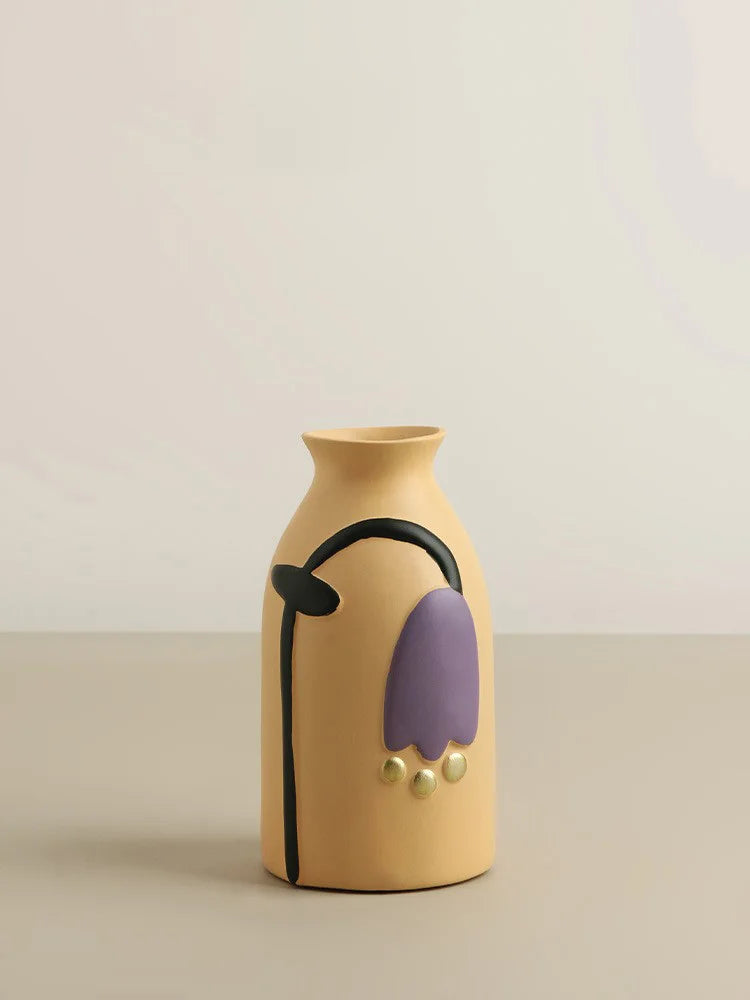 Yellow vase with purple and black decorative elements on a beige background