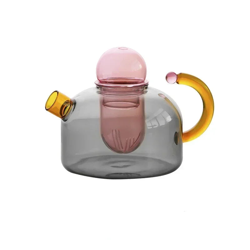 Glass teapot with pink lid and yellow accents on a white background