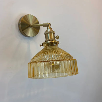 Gold wall-mounted lamp with ribbed glass shade on a white background