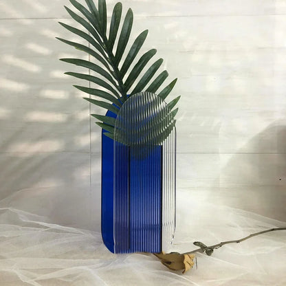 Blue vase with a green leafy plant against a light background