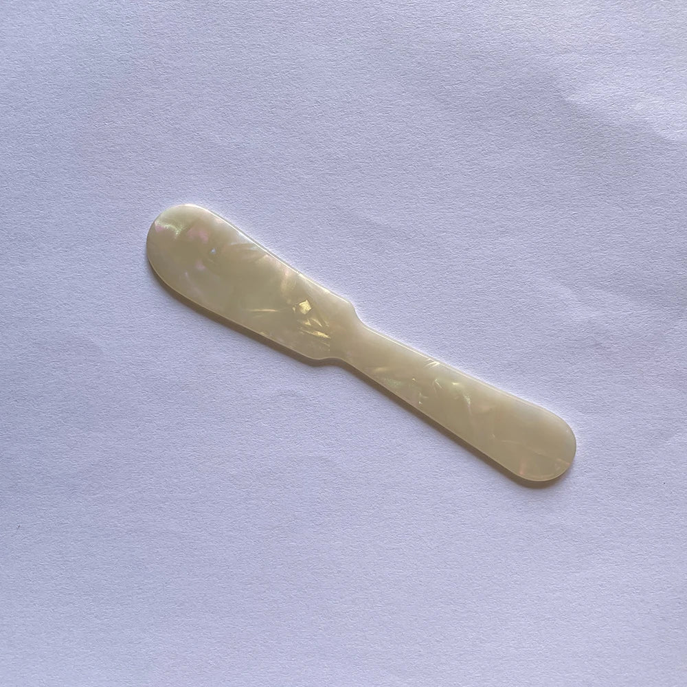 Gold butter knife on a light purple fabric background