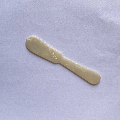 Gold butter knife on a light purple fabric background