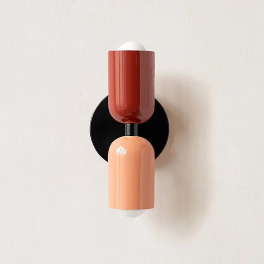 Wall sconce with red and peach-colored cylindrical design on a light gray background