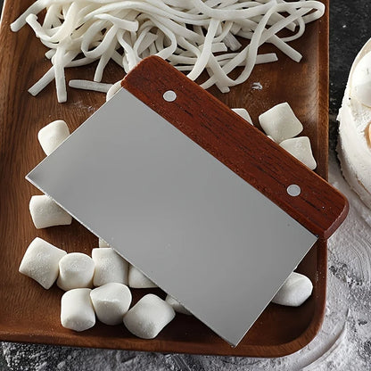 Small cleaver on a wooden cutting board with marshmallows and noodles.