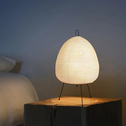 Woven table lamp on a wooden surface with a soft glow against a neutral background