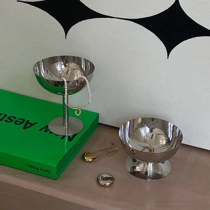 Two metallic bowls on a surface with a green book and decorative items.