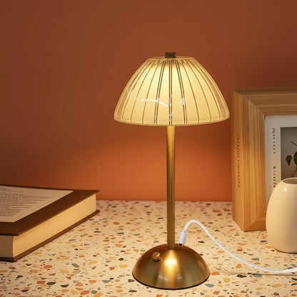 A glass fluted lamp stood on a terazzo work surface with a book to the left and a picture frame on the right.