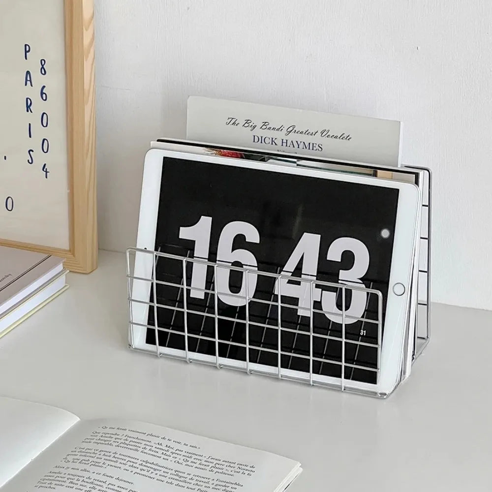Digital clock displaying time on a white surface with books and a frame in the background