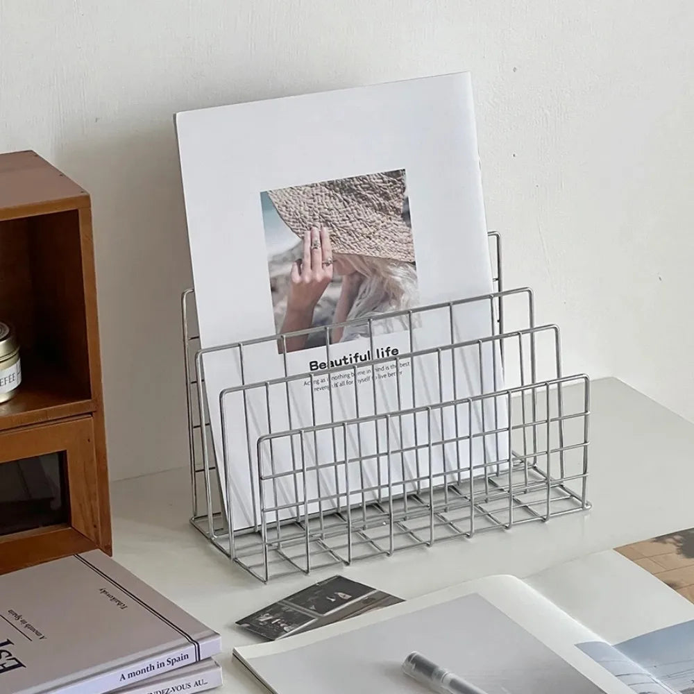 Metal magazine holder with a photo and books on a desk