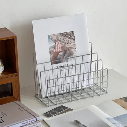 Metal magazine holder with a photo and books on a desk